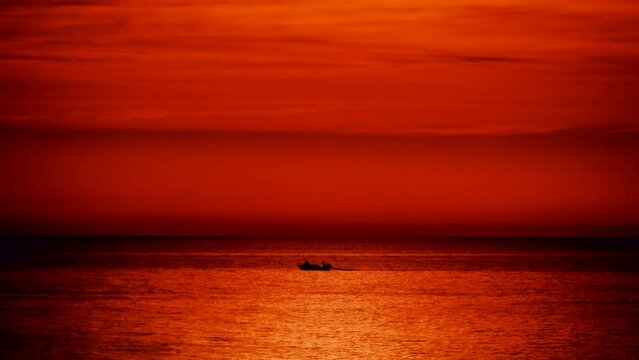 Fishing boat on sea at sunrise. Seascape in the morning. Orange color sky and water.