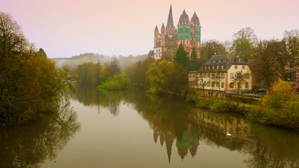 Fototapeta na wymiar mächtiger Limburger Dom spiegelt sich im Morgenrot im Fluss Lahn