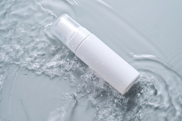 Bottles of cosmetic products in water on a blue background.