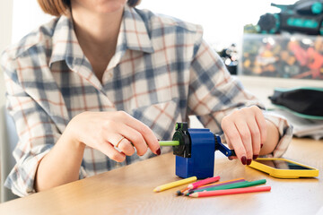 Close-up shot of a girl sharpening pencils using a special creative sharpener	