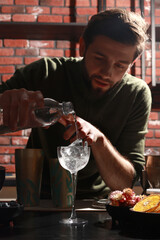 The process of preparing an alcoholic cocktail. The bartender mixes a cocktail in a shaker. Nightlife, night bar atmosphere. Recipe for delicious cocktails, mixology.
