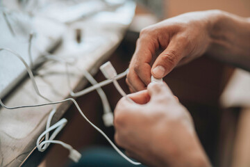  Entangled Solutions - A close-up of hands meticulously selecting the right cable from a tangled...