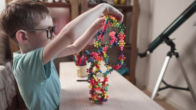 A child boy in the children's room is playing with a toy constructor for teaching the science of chemistry. Assembling molecules from elements. Children's scientific education