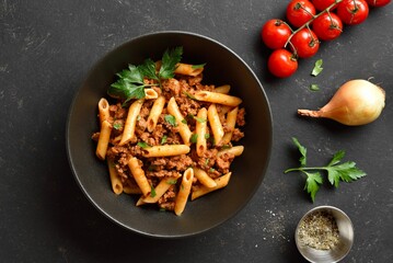 Penne pasta with minced meat, tomato sauce and greens. Top view, flat lay