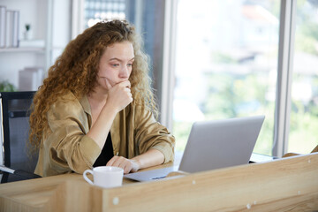 young woman working on laptop computer and feeling tired and worry from hard work in the office