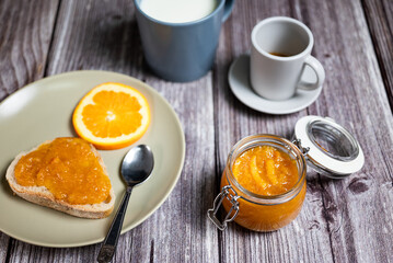 Healthy breakfast with homemade orange marmalade. Breakfast with slice of bread with jam, coffee and a cup of milk