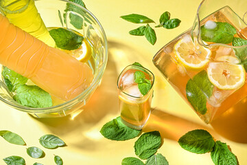 Ice tea with lemon and mint in a yellow and summer background with cutting light