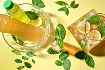Ice tea with lemon and mint in a yellow and summer background with cutting light
