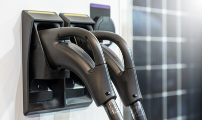 Close up of electric car charging station on the background of solar panels.