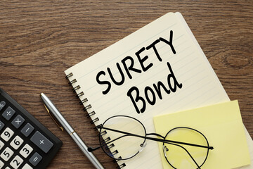 Surety bond glasses lie on a notepad near the calculator. text