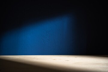 Table on dark blue wall background. Minimalist composition with abstract shadow on the wall and...