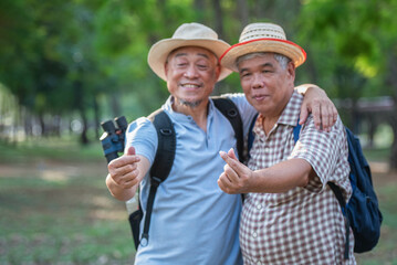 Blurred image of two elderly Asian men hugging their necks and raising their hands to make small hearts. Tourists are impressed with the tour guides.