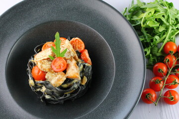Black spaghetti. Black seafood pasta in white plate on black background with copy space.