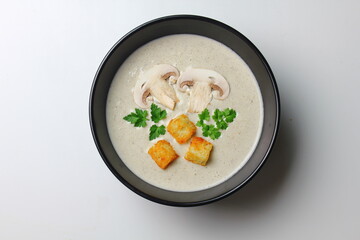 Mushroom cream soup with cream, croutons and herbs on a white wooden background. Delicious comfort food