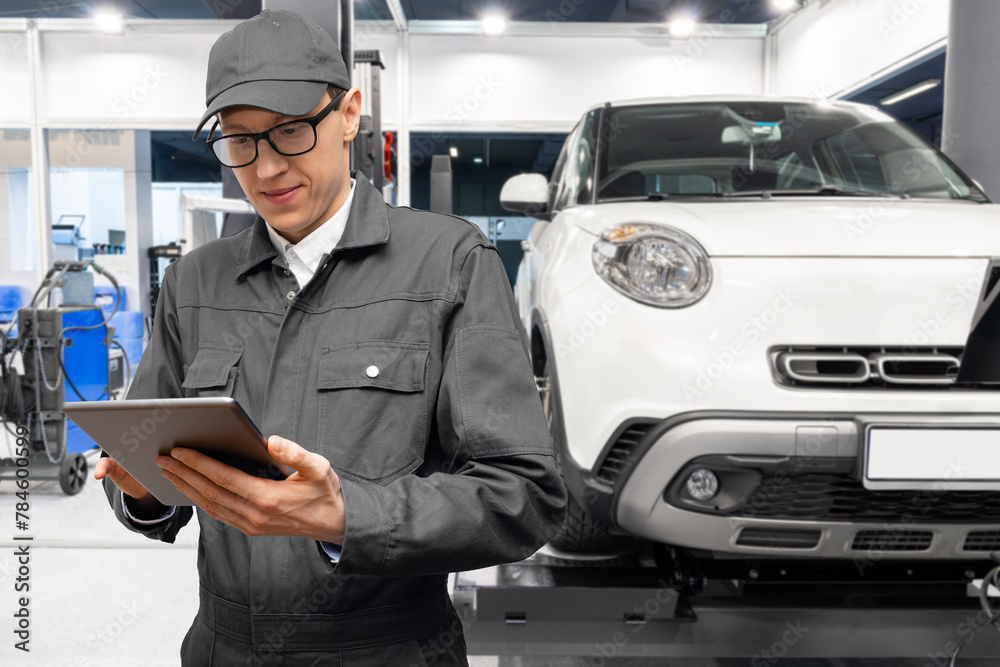 Poster serviceman with digital tablet on the background of the car in the car service.