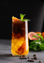 Coffee with orange juice (bumble) in a tall glass with ice and mint on a dark background