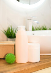 Various types of chemicals for washing clothes on wooden table overlooking modern bathroom. Washing powder, detergent. Concept of order and cleanliness in house. Vertical photography.