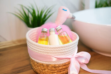 Children's cosmetics, bath accessories and toys in wicker basket in bright bathroom. Children's...