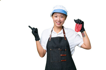 Young caucasian woman wearing an apron and serving fresh cut meat over isolated background pointing finger to the side