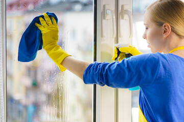 Woman cleaning window at home - 784622512