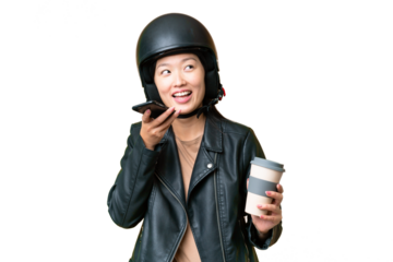 Young Asian woman with a motorcycle helmet over isolated chroma key background holding coffee to take away and a mobile