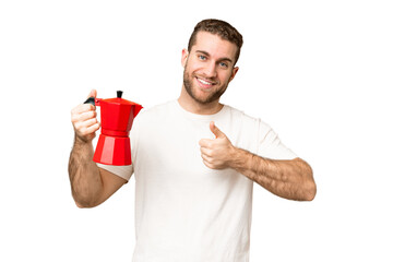 Young handsome blonde man holding coffee pot over isolated chroma key background with thumbs up...