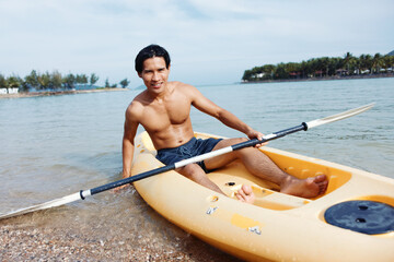 Serenity in Motion: A Happy Asian Man Kayaking on a Tropical Beach