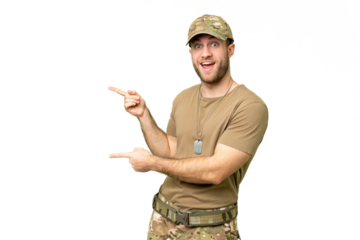 Military with dog tag over isolated chroma key background surprised and pointing side