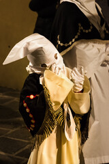 Hooded child with big gloves during the famous Good Friday procession - 784629712