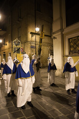 Hooded penitents during the famous Good Friday procession in Chieti (Italy) carry the cross with the effigy of Jesus - 784629738