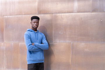 A young man in a blue hoodie stands in front of a wall