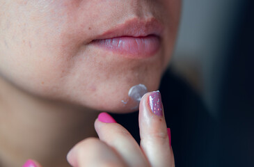 latina woman's mouth and chin applying moisturizer in that area