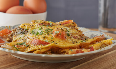 Morning meal mushroom and tomato omelette garnished with seasoning and herbs.