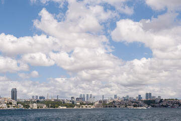 Fototapeta premium panoramic view of the skyline of the financial center of Istanbul seen from the Bosphorus, with the Dolmabahce palace under a cloudy sky, copy space