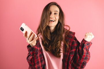 Amazed brunette woman wear red plaid shirt and pink pullover look surprised wow on pink background....