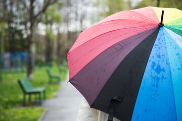 Woman holding colorful umbrella in park , rear view . Close up
