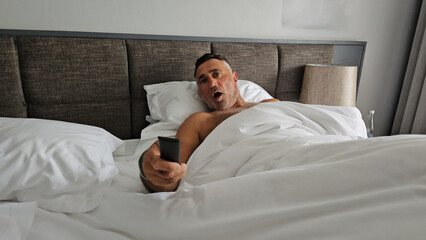 Shocked man sitting on the couch and watching tv at home