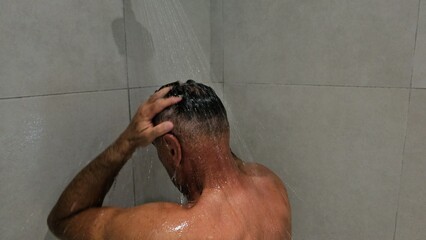 Man Standing in Shower With Head Under Water