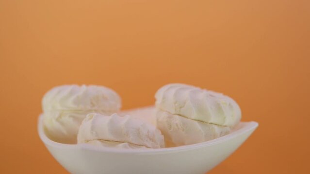 Seamless circular motion: some sweet marshmallows on a plate on a brown background.
