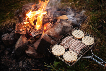 Grilling sausages. Concept of resting in the fresh air, frying sausages on the grill. Sausages,...