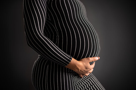 Elegant Pregnant Woman in Striped Dress Holding Her Belly