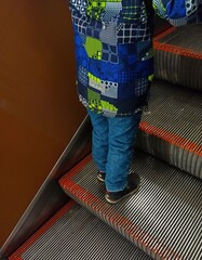 Rear view of a little boy standing on a subway step in the background. Public urban transport...