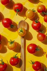 Fresh Cherry Tomatoes on a Yellow Background with Wooden Spoon
