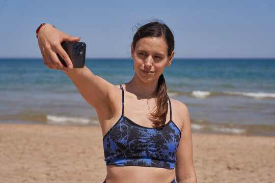 Healthy woman in sportswear doing selfie on the beach