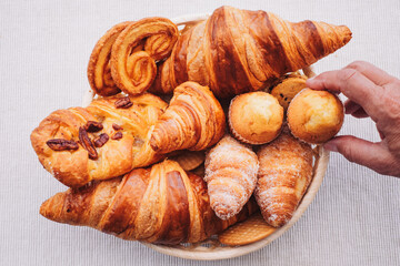 Sweet bakery products and croissant in the basket captured from above (top view), white background