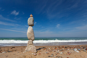 Rock zen pyramid of stones of different shapes on a background of blue sky and sea.