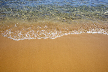 Transparent sea water on a sandy beach close-up.