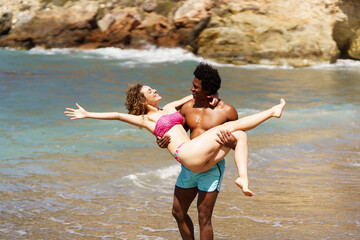 Diverse couple having fun on beach in daylight - 784712975