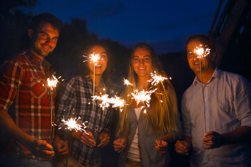 Young happpy people with sparklers having fun