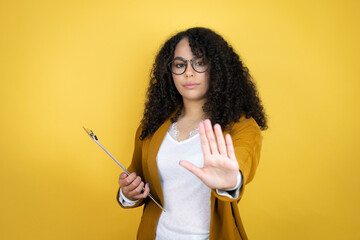 African american business woman with paperwork in hands over yellow background serious and doing stop sing with palm of the hand.
